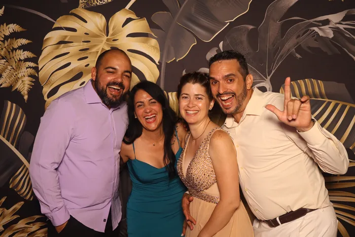 Friends celebrating a birthday in front of a black and gold photo booth backdrop