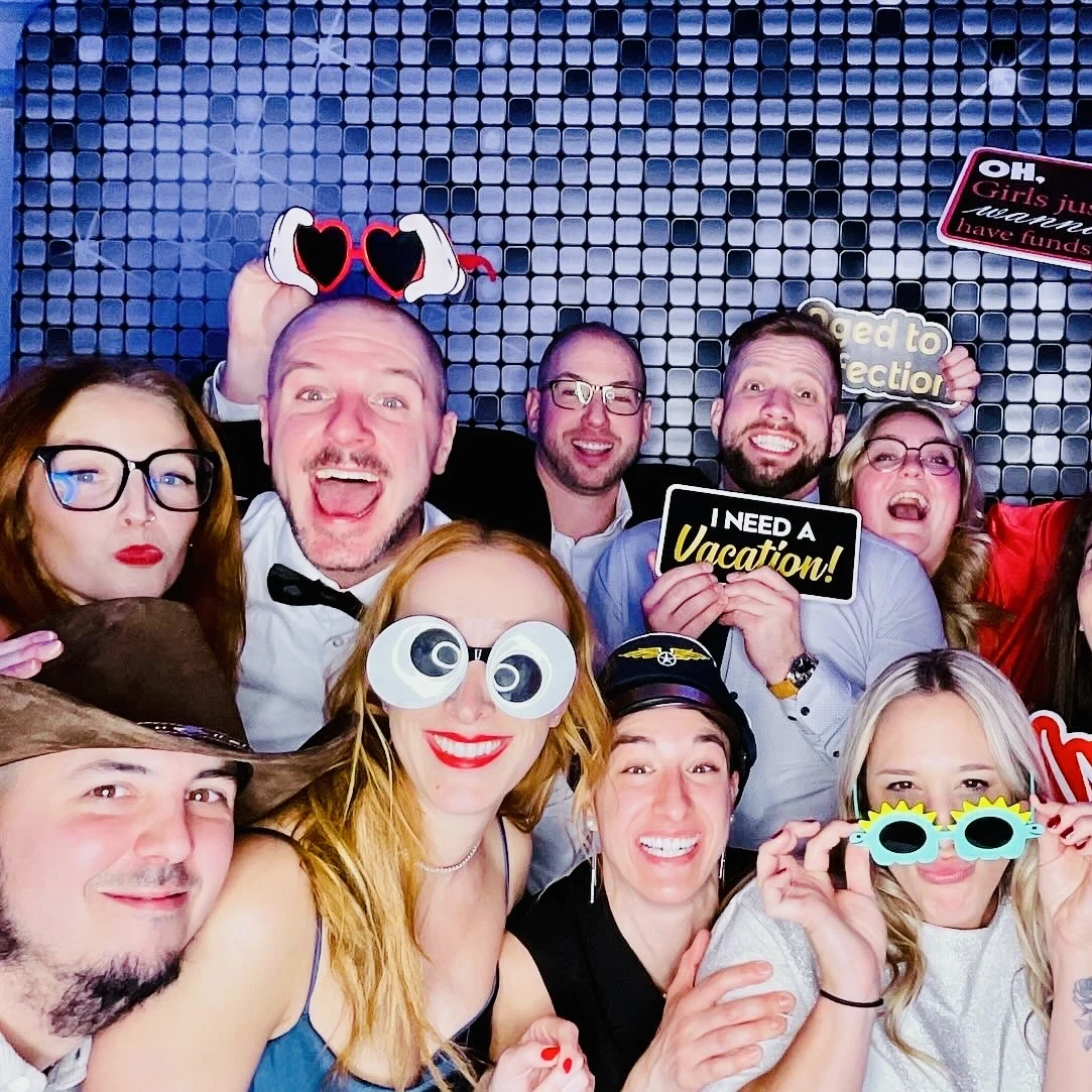 Colleagues laughing together with props at the photo booth during a Miami corporate event