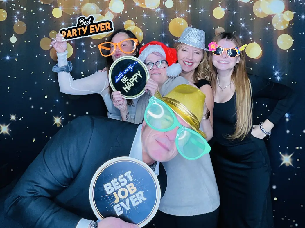 Colleagues with Best job ever props at the photo booth during a Miami company holiday party