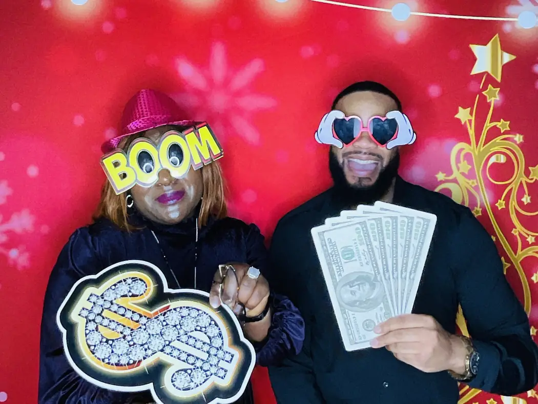 Guests with props at the photo booth against a red backdrop at a Miami corporate party