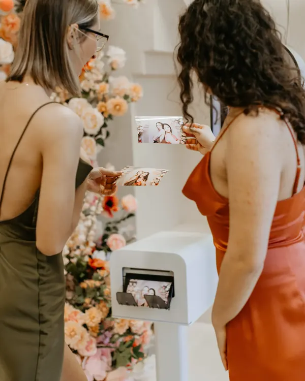 Two guests holding fresh photo prints beside the DSLR booth printer