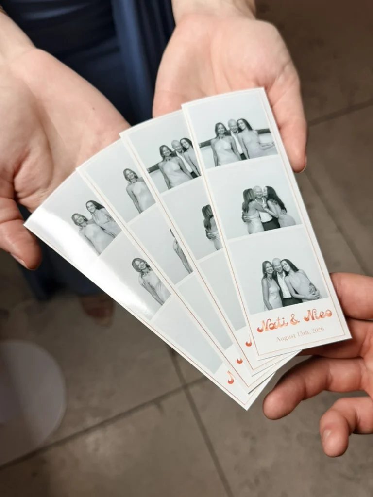 Several black-and-white Glam photo booth strips held in guests' hands