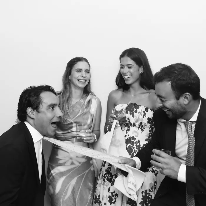 Wedding guests laughing with a tie prop in the black-and-white Glam Booth