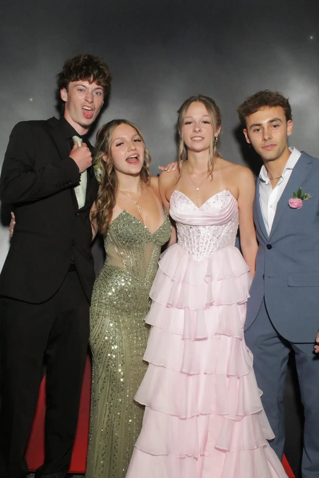 Two couples in prom formalwear at the photo booth