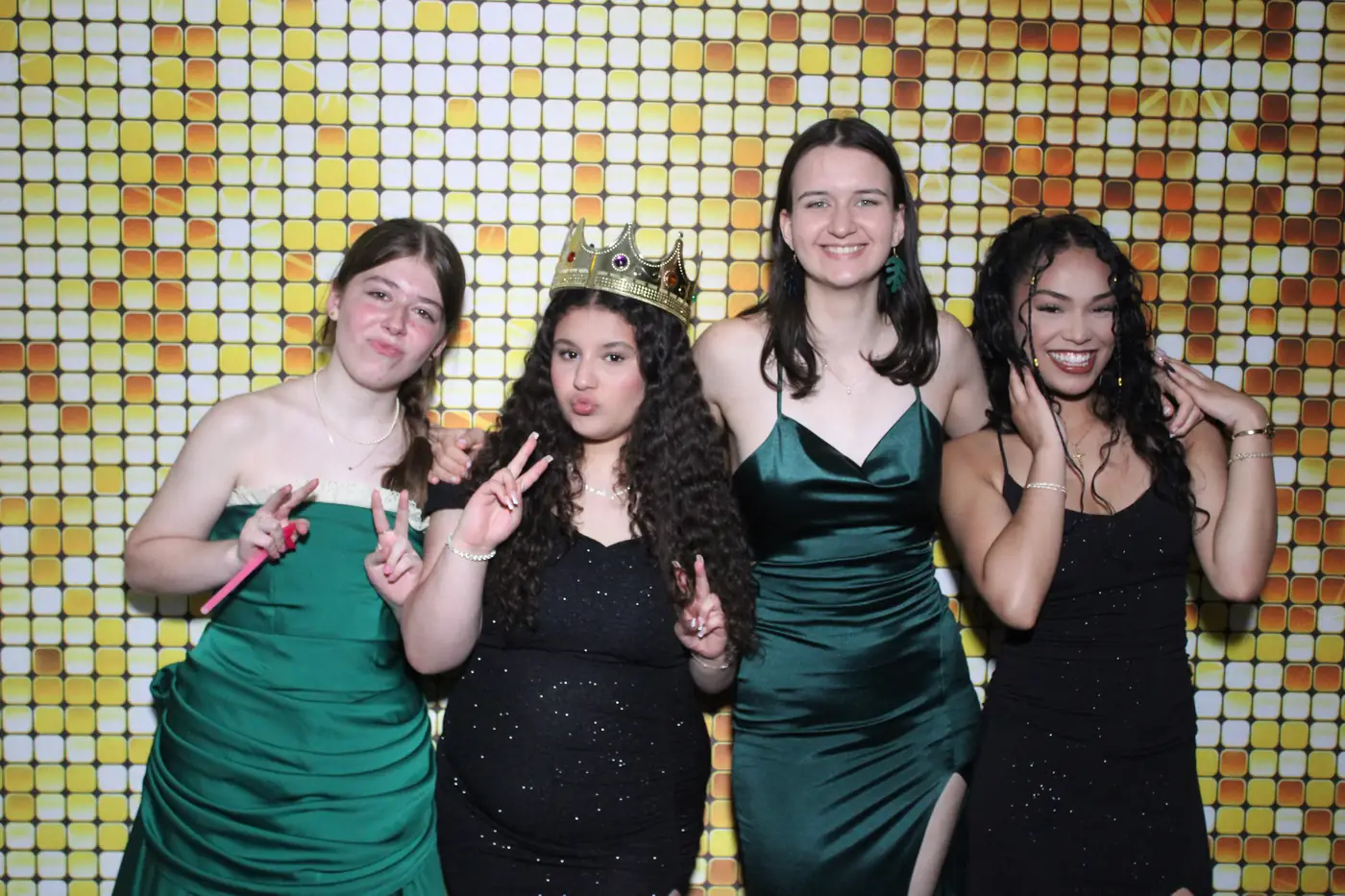 Friends in prom dresses posing together at the photo booth