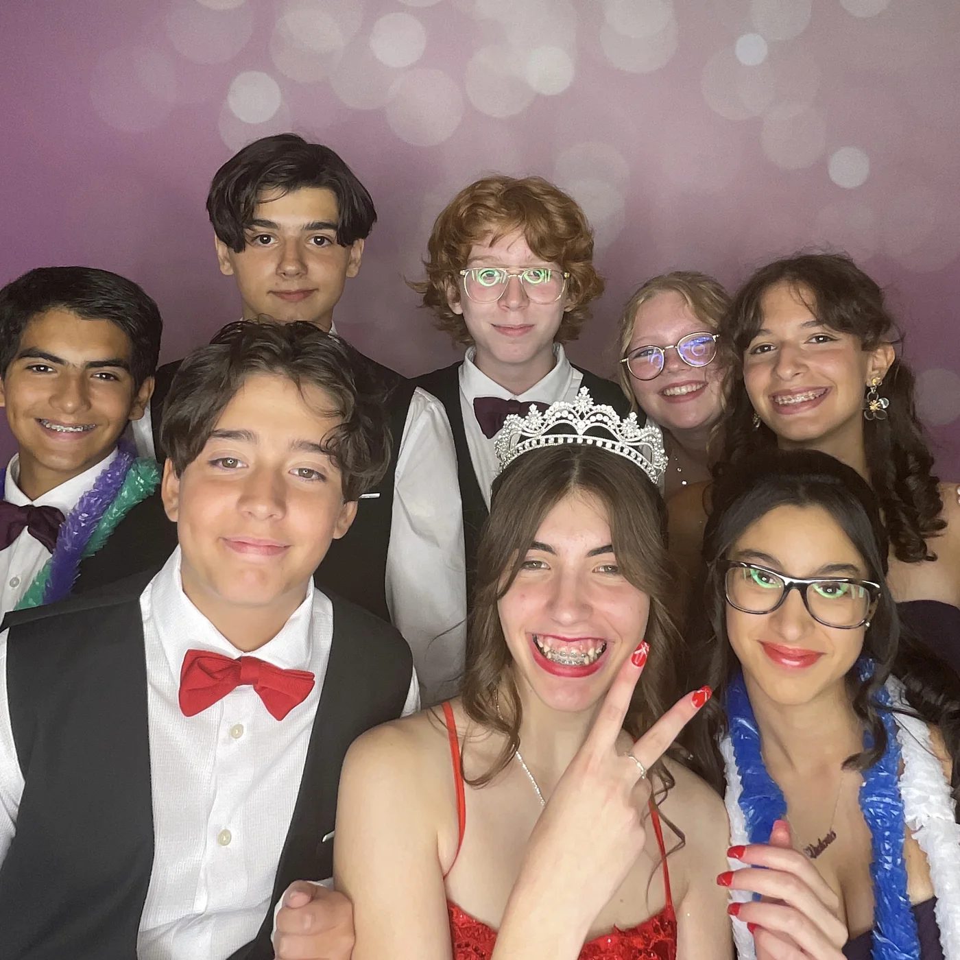 Quinceañera and friends laughing together in a crowded photo booth portrait