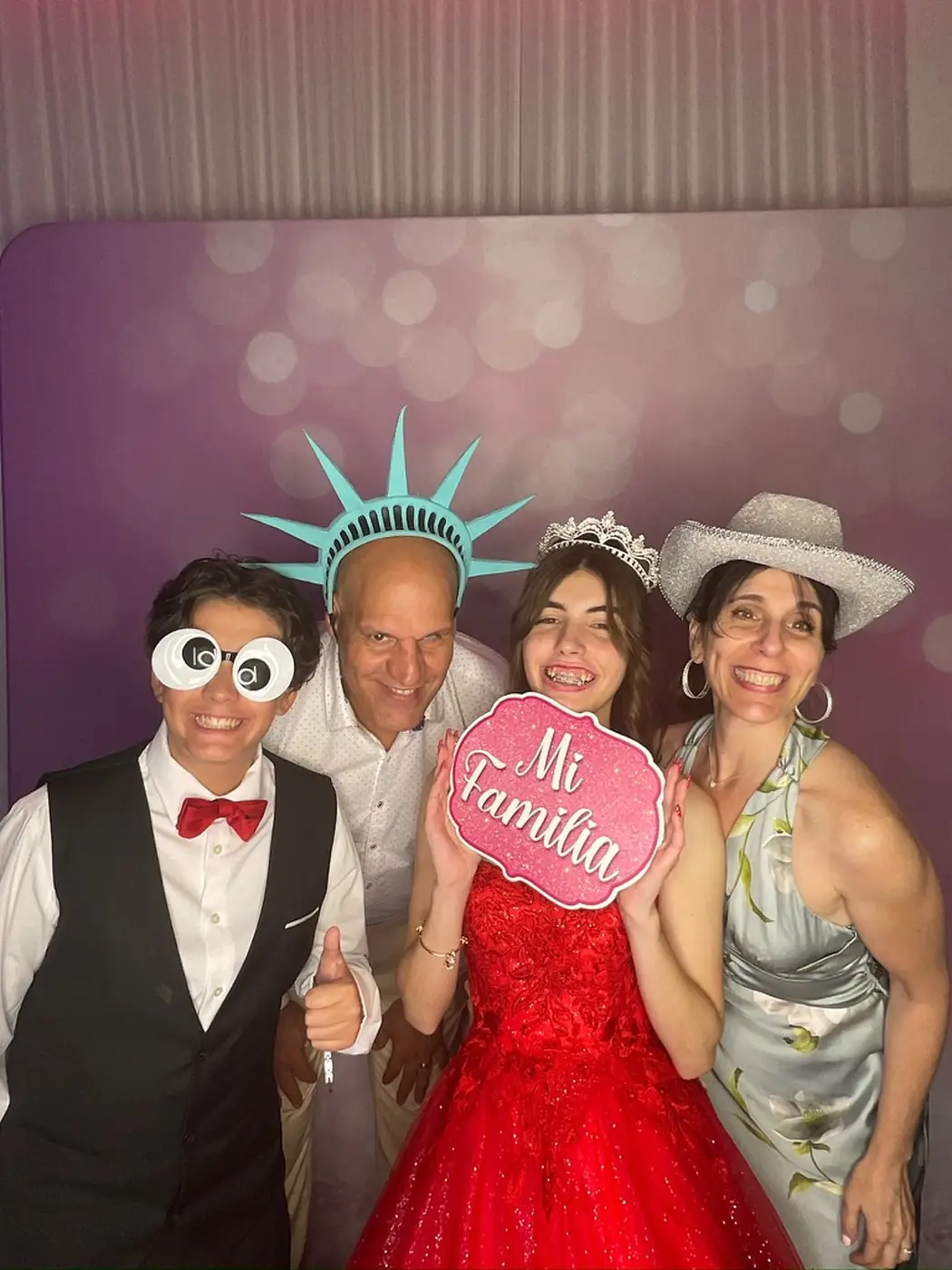 Quinceañera posing with family members and a Mi Familia sign at the photo booth