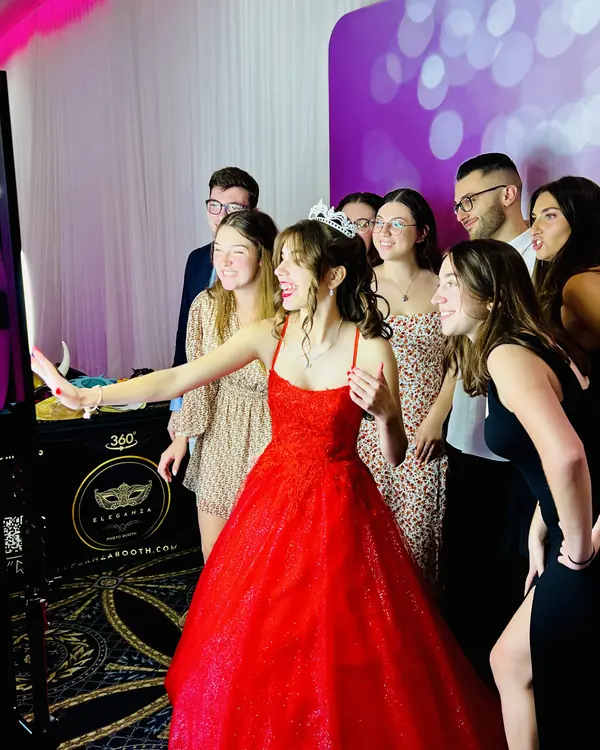 Quinceañera in a red gown taking photos with her court at a Miami photo booth