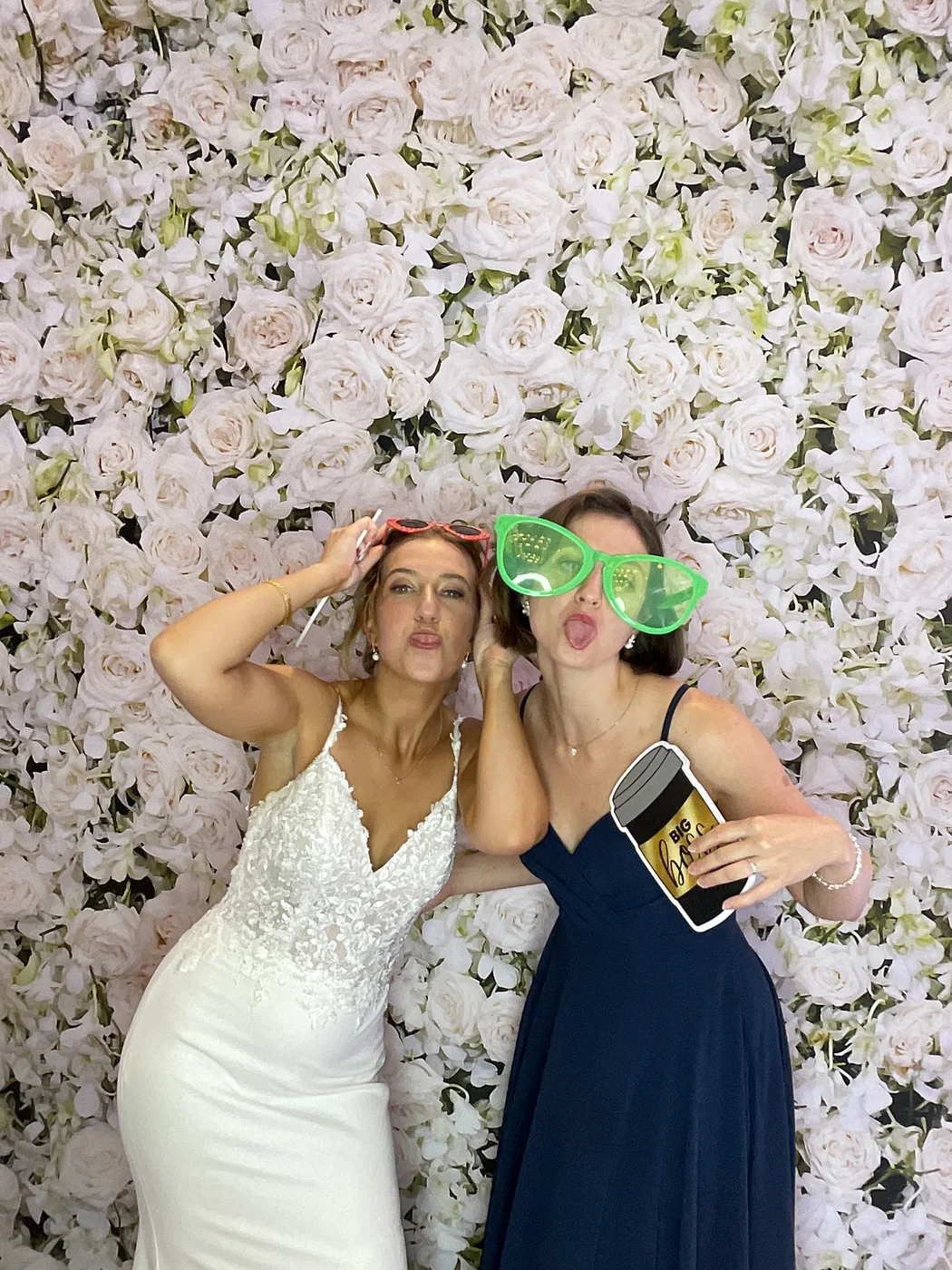 The bride and a friend with novelty glasses at the photo booth at a wedding in Aventura