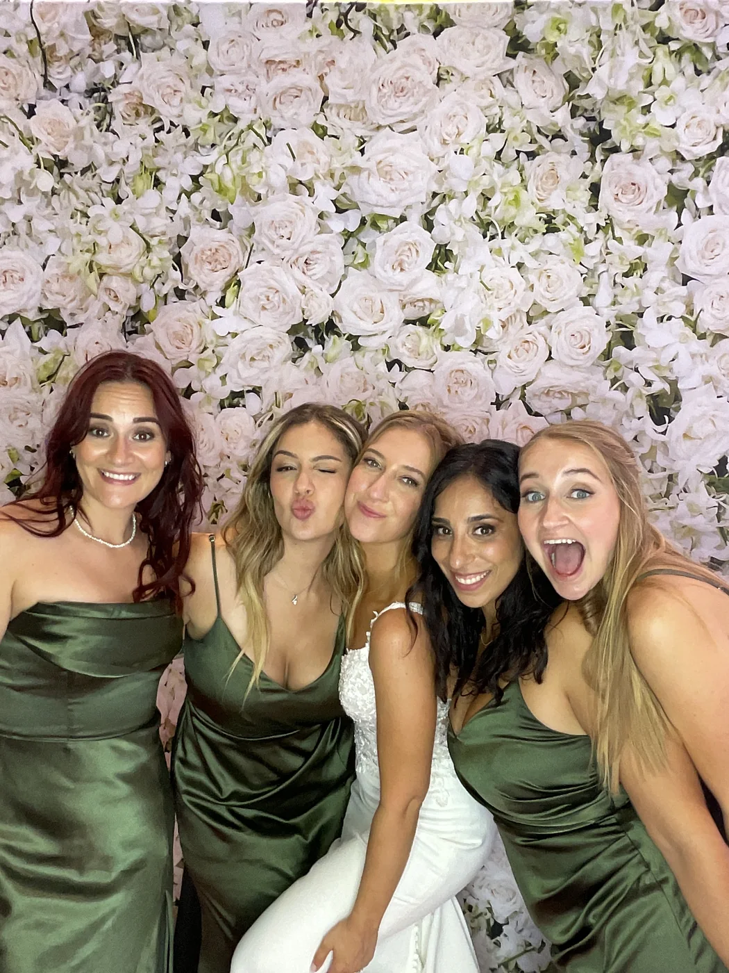 Bride and bridesmaids at the photo booth with a floral backdrop at a wedding in Aventura
