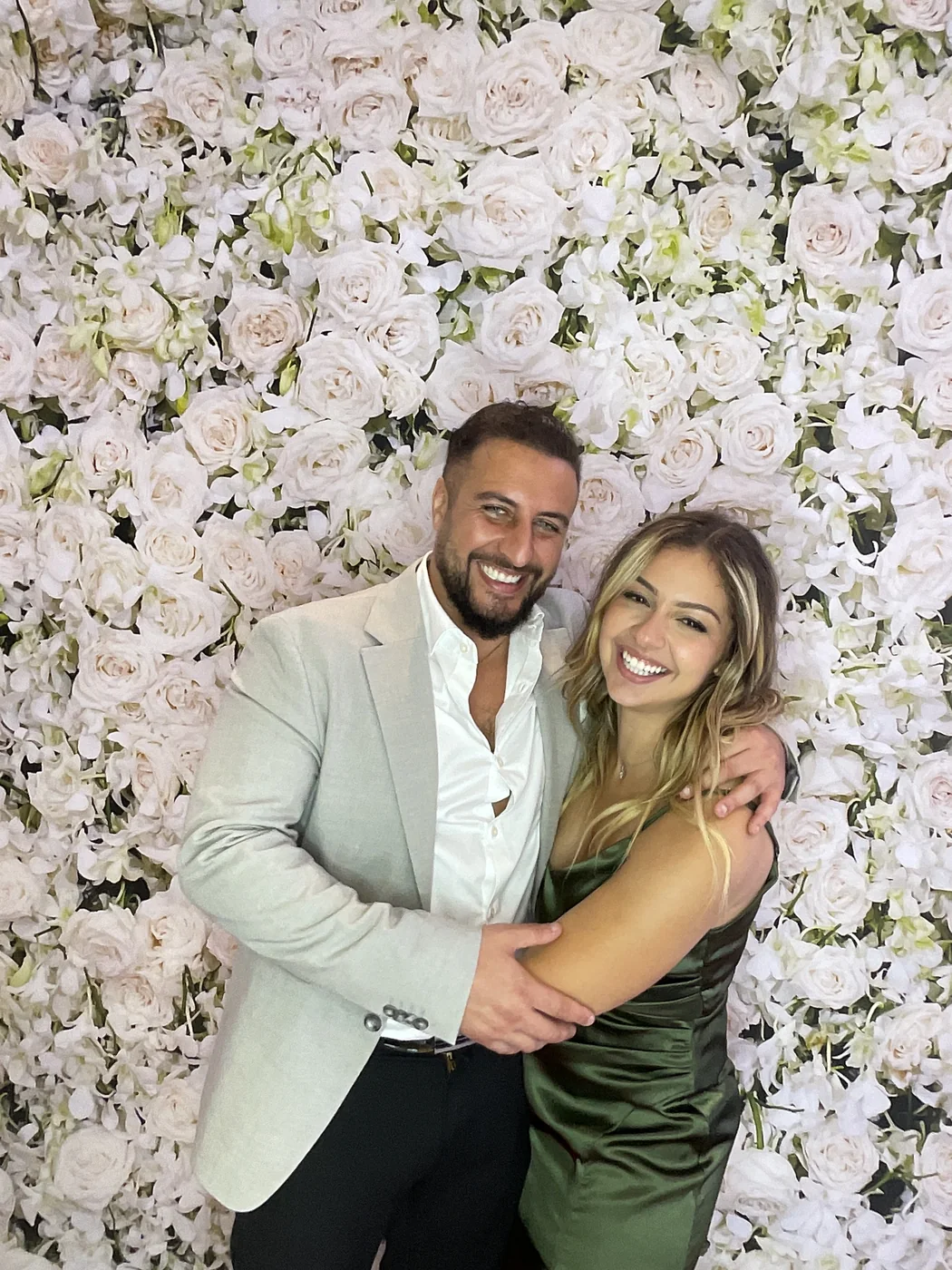 A couple embracing at the photo booth with a floral backdrop at a wedding in Aventura