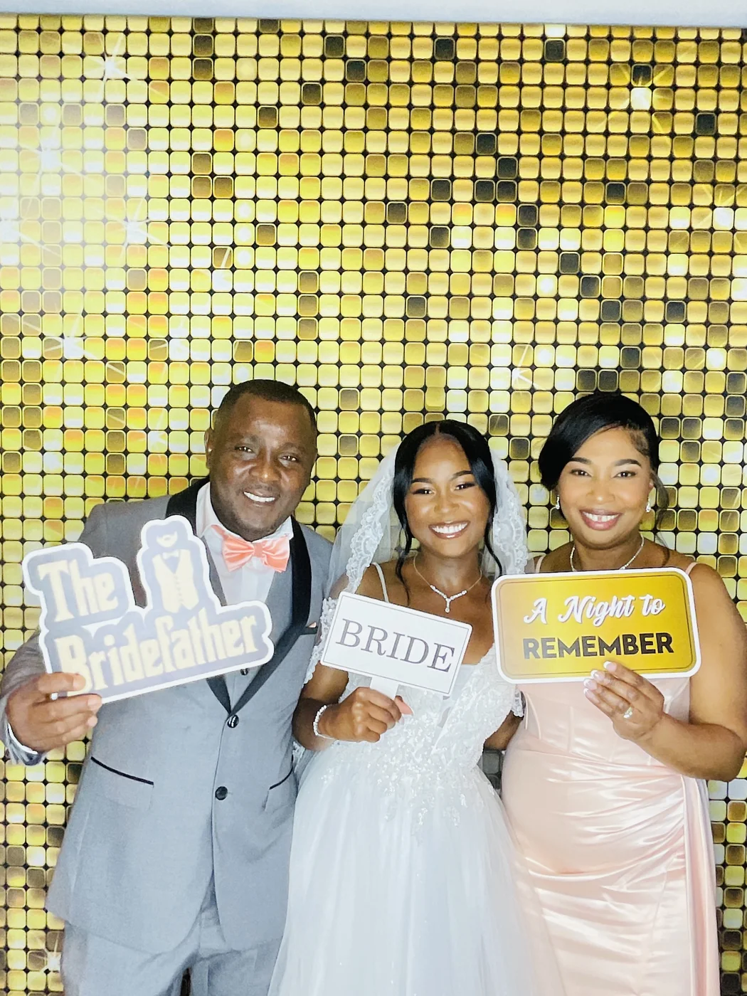 The bride with her parents holding props at a Miami wedding photo booth
