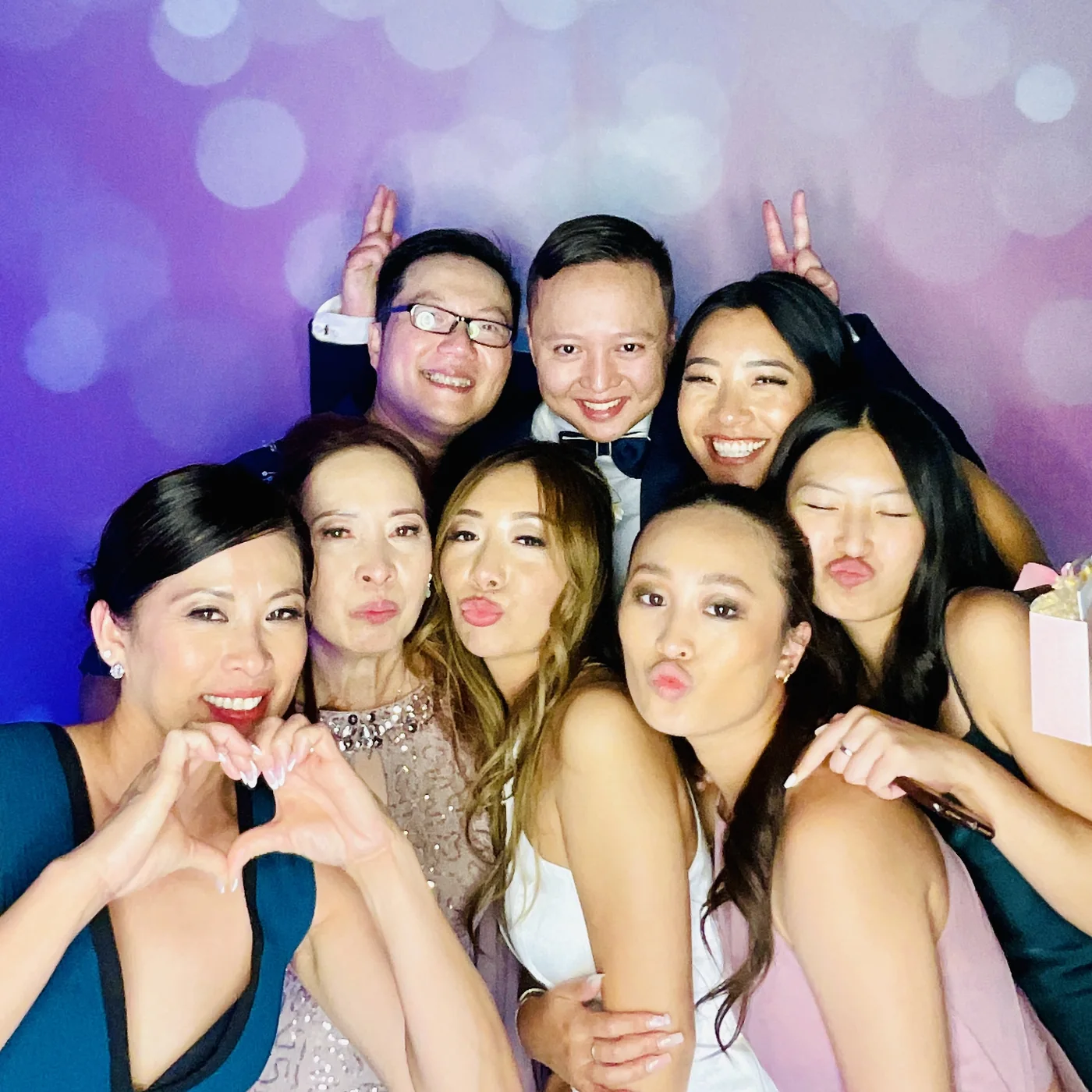 Wedding guests crowded into the photo booth against a bokeh backdrop