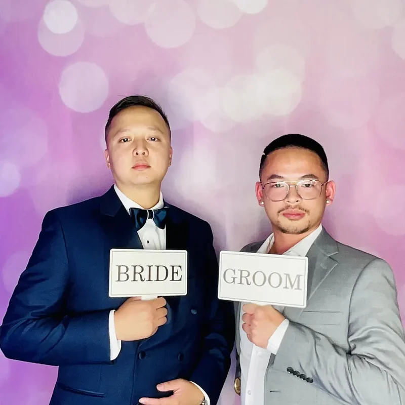 Newlyweds holding bride and groom signs at their Miami wedding photo booth